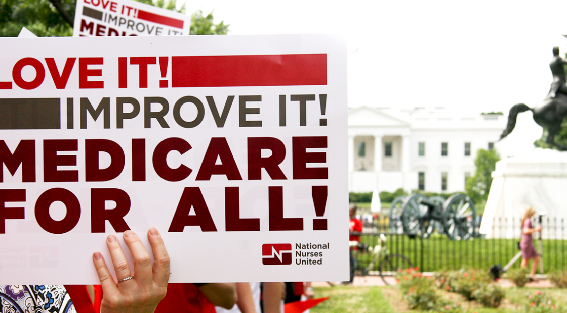 Holding sign in front of a Capitol building "Love it! Improve it! Medicare for all!"