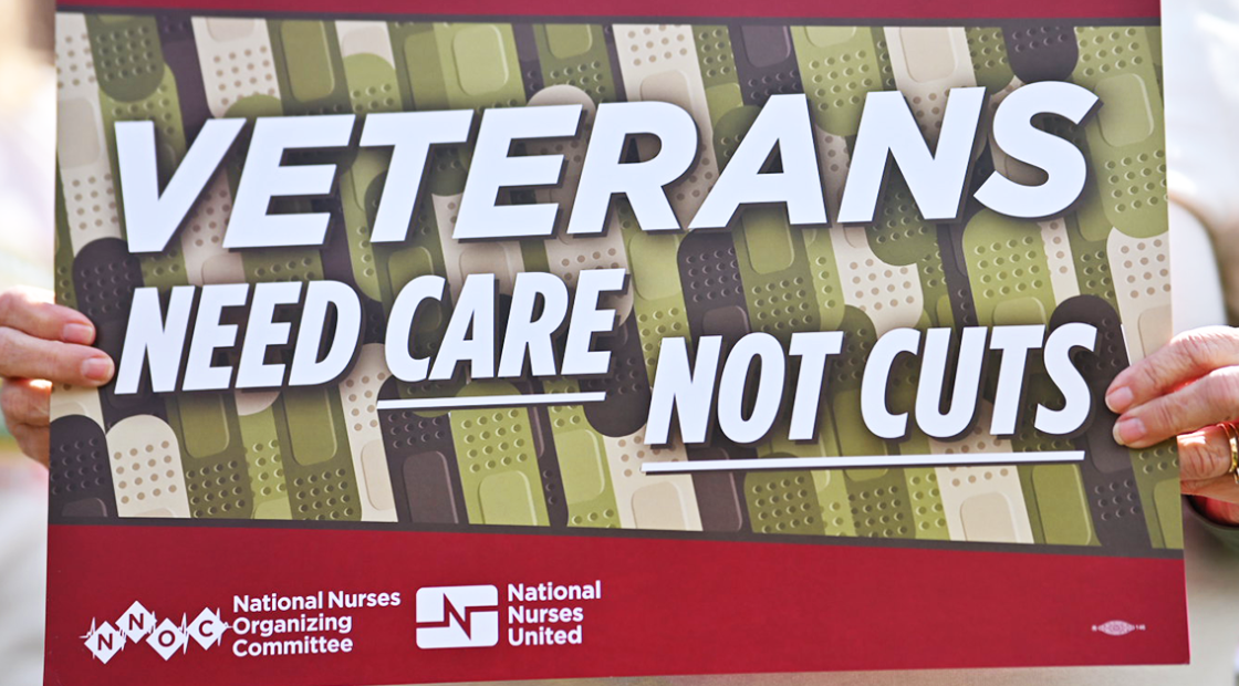 Nurse holding sign "Veterans need care not cuts"