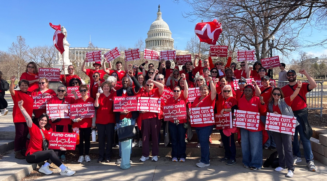 Seven nurses standing in front of U.S. capitol building, smiling, with raised fists, holding signs "Some Cuts Don't Heal"