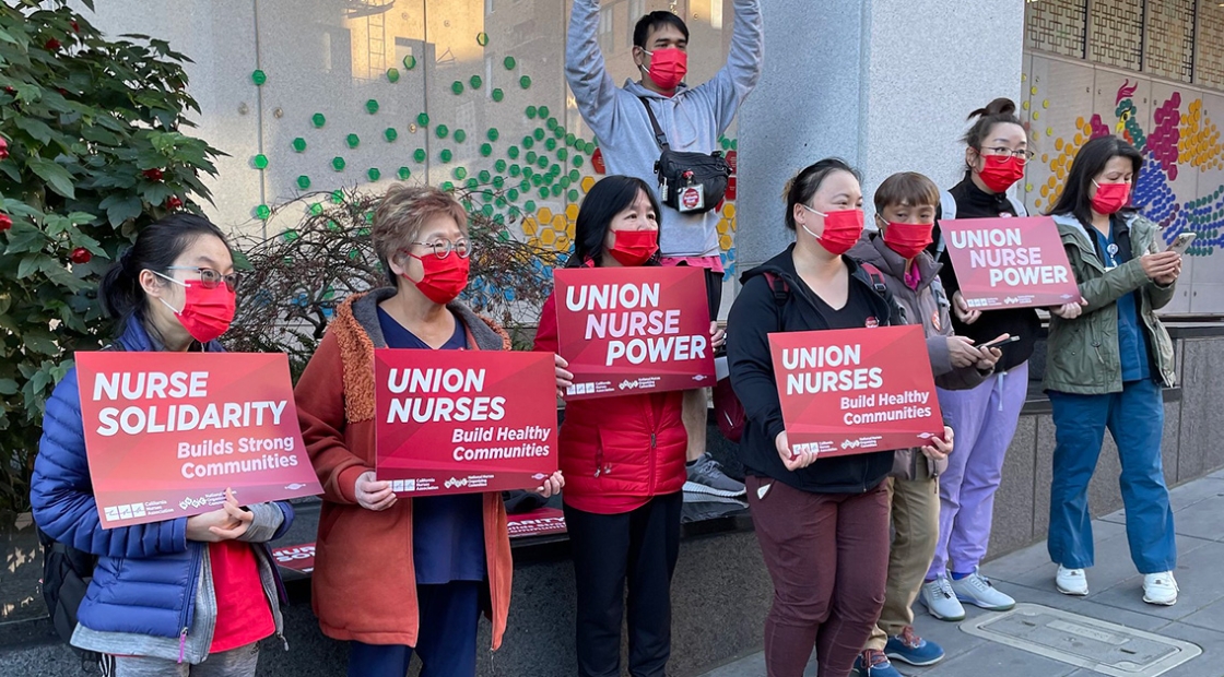 Group of nurses outside Chinese Hospital holding signs "Union Nurses Build Healthy Communities"