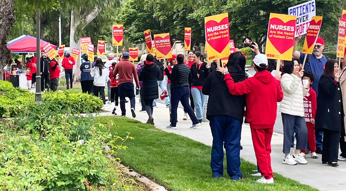 Nurses holding signs on a grassy knoll and sidewalk: "Nurses are the heart of patient care"