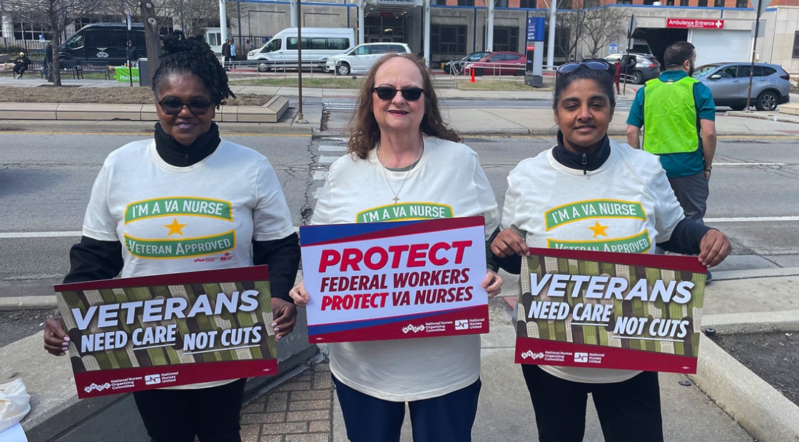 Three nurses outside hospital holding signs "Veterans Need Care Not Cuts" and "Protect Federal Workers"