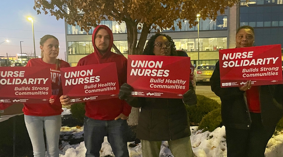 Four nurses outside Research Medical Center holding signs "Union Nurses Build Healthy Communities"