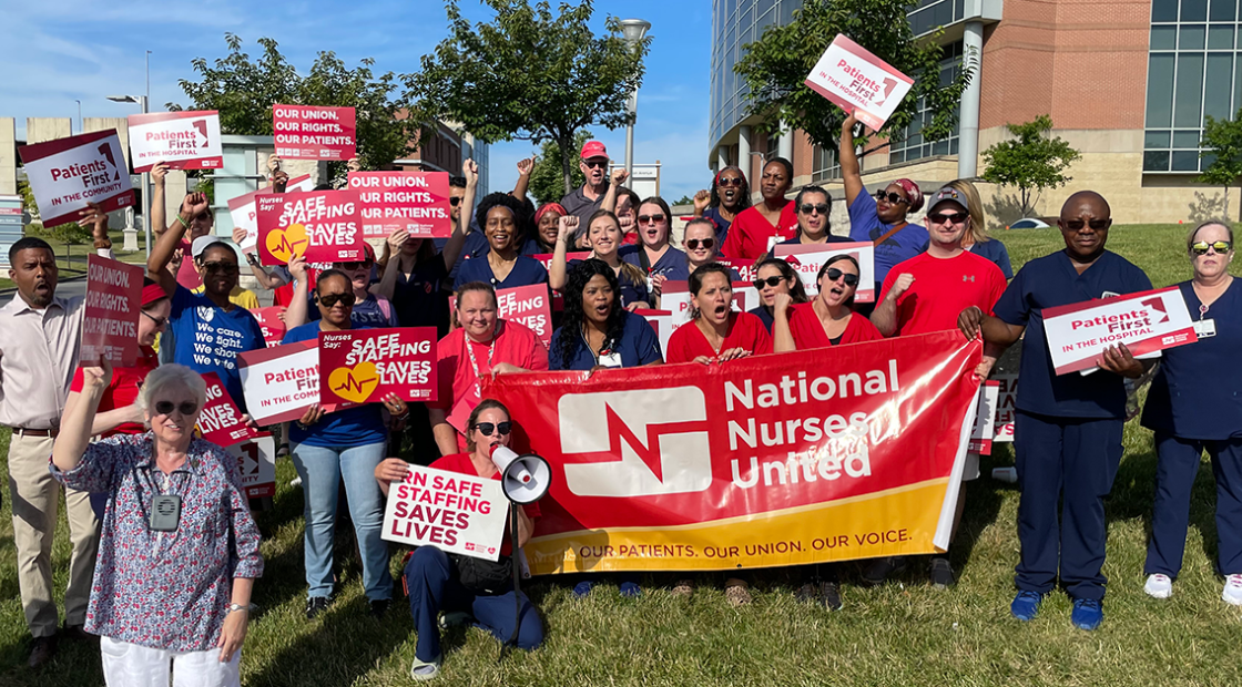 Nurses in front of St Agnes with signs: "RN Safe Staffing saves lives" and "Patients 1st in the hospital" and a "Natioanal Nurses United" banner