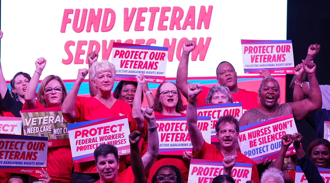 Group of nurses with raised fists holding signs supporting veterans and VA nurses