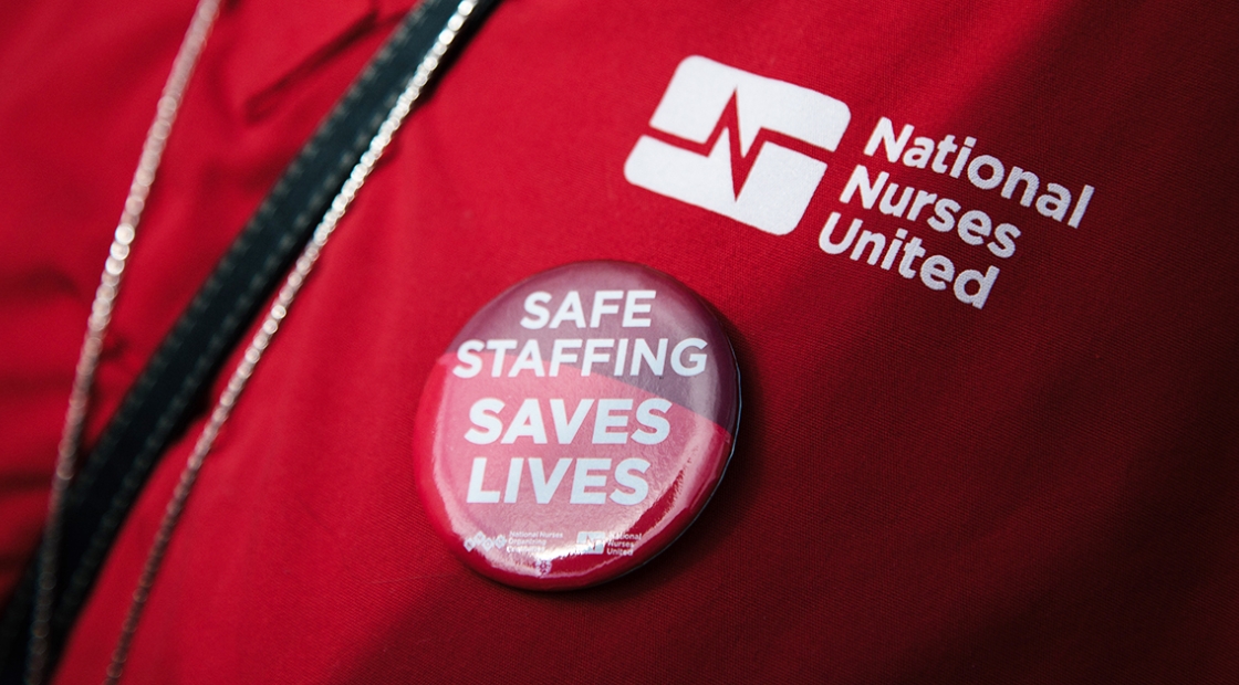 Button with "Safe Staffing Saves Lives" on scrub with "National Nurses United"