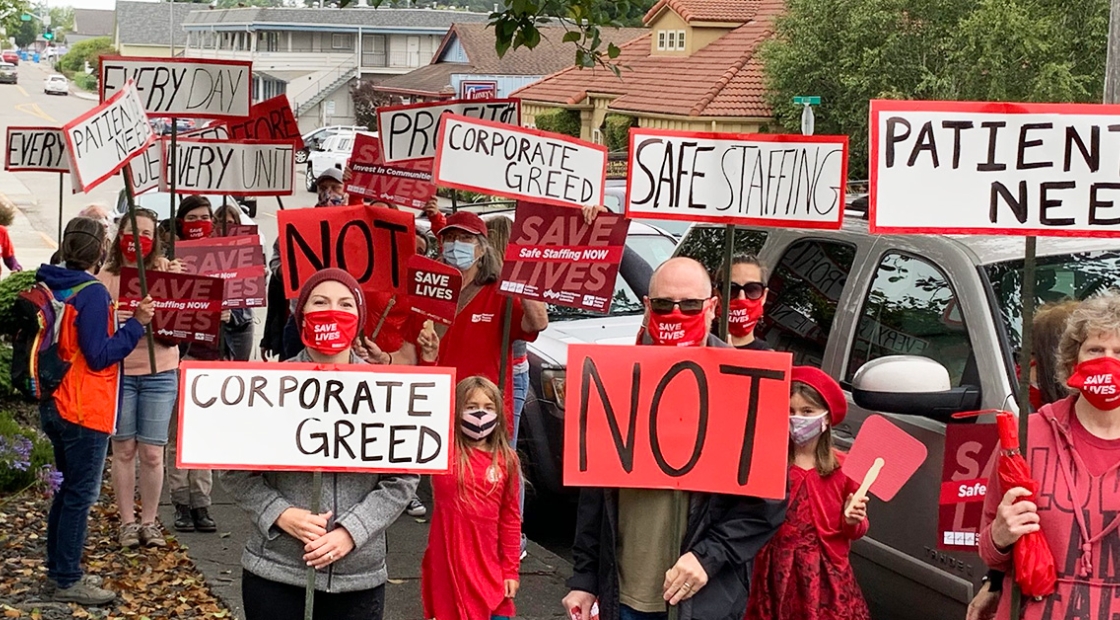 Large group of nurses and community holding signs calling for safe staffing 