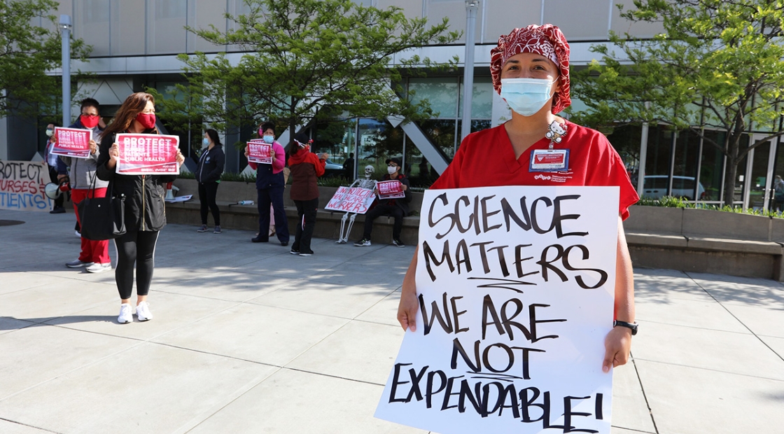 Nurse holds sign "Science Matters, We Are Not Expendable"