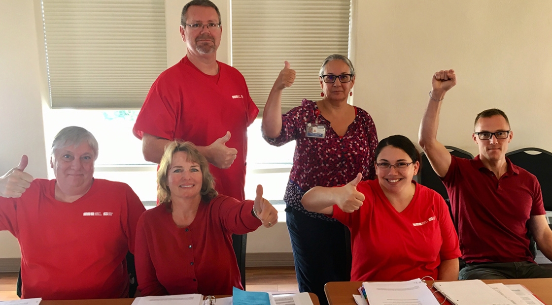 Group of nurses at table giving thumbs up