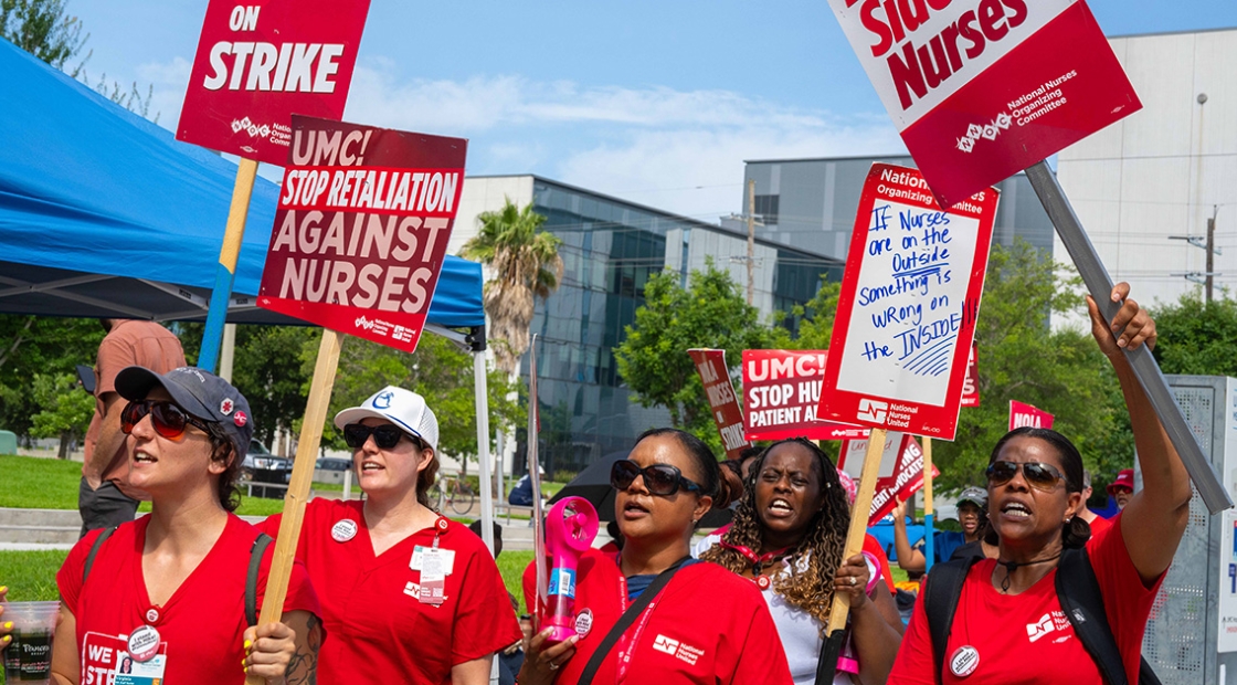 Nurses standing outside, holding signs calling for a fair contract