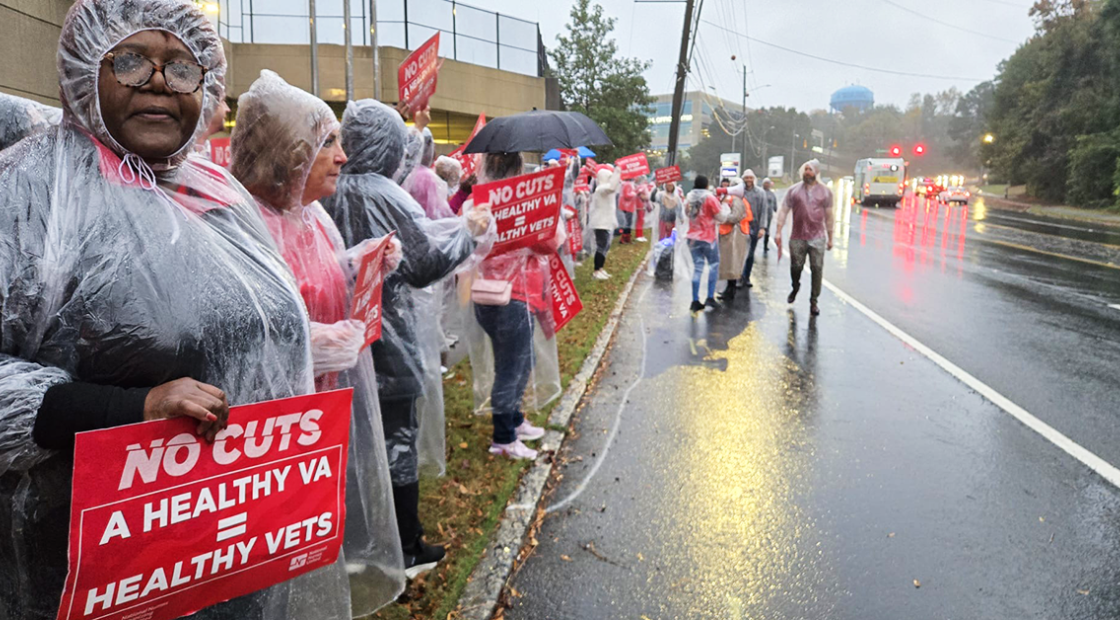 Nurses standing in rain along street with signs: "No cuts: A healthy VA = healthy vets"