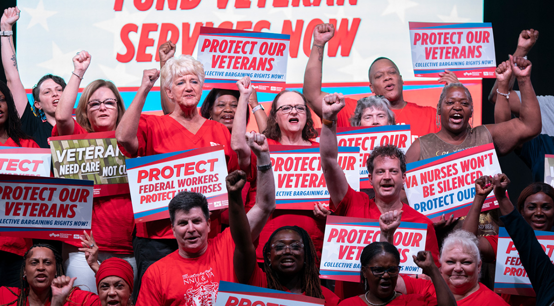 Group of nurses with raised fists holding signs supporting veterans and VA nurses