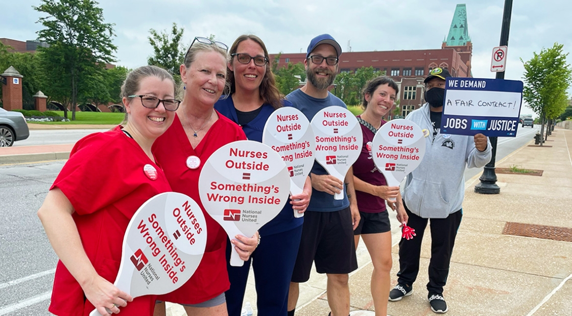 Group of nurses outside holding signs "Nurses Outside = Somethings Wrong Inside"