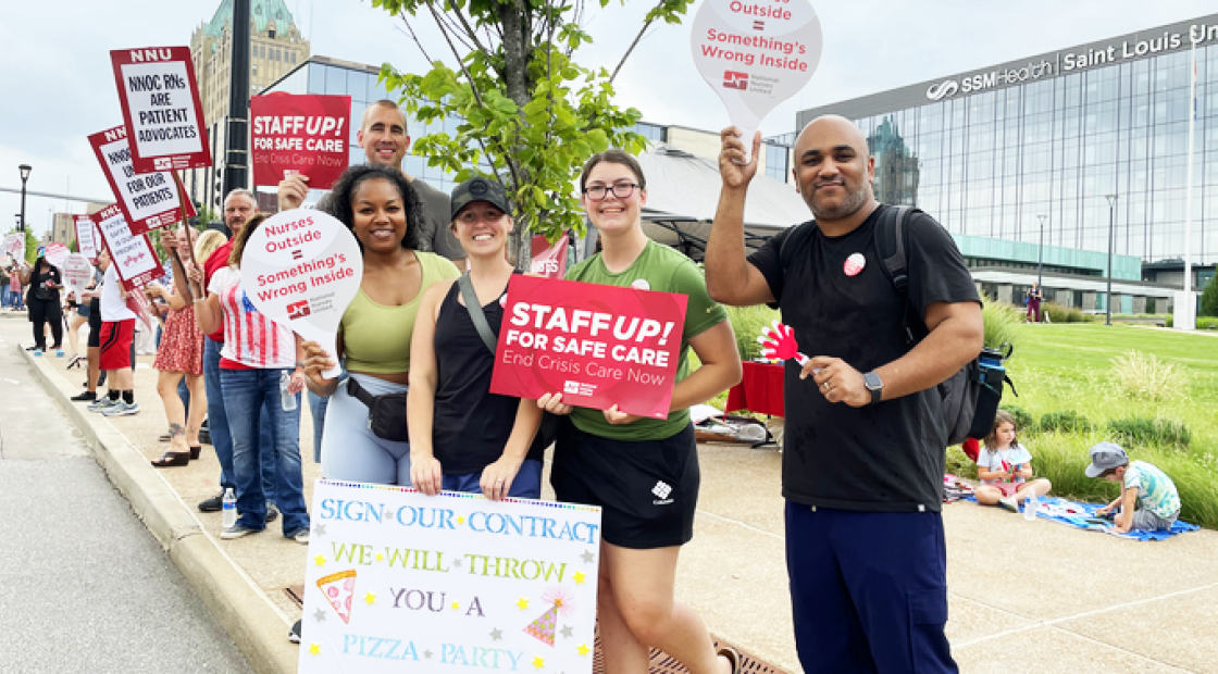 Nurses in front of Saint Louis University Hospital holding signs like "Staff up for safe care!"