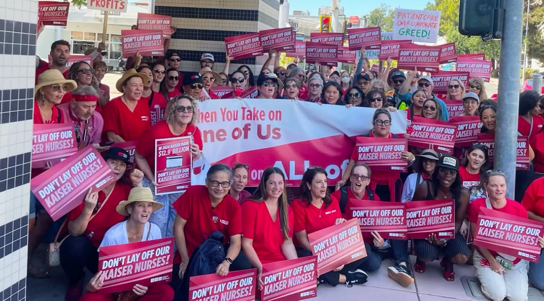 Large group of nurses holding signs "Don't lay off our Kaiser nurses"