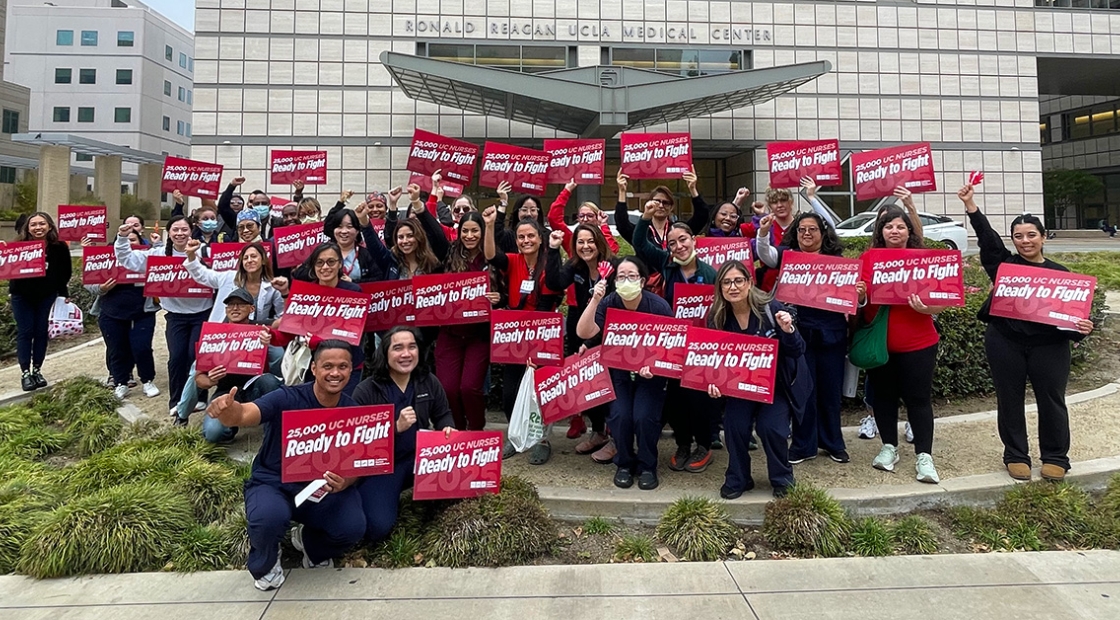 Large group of nurses outside holding signs "Ready to Fight"