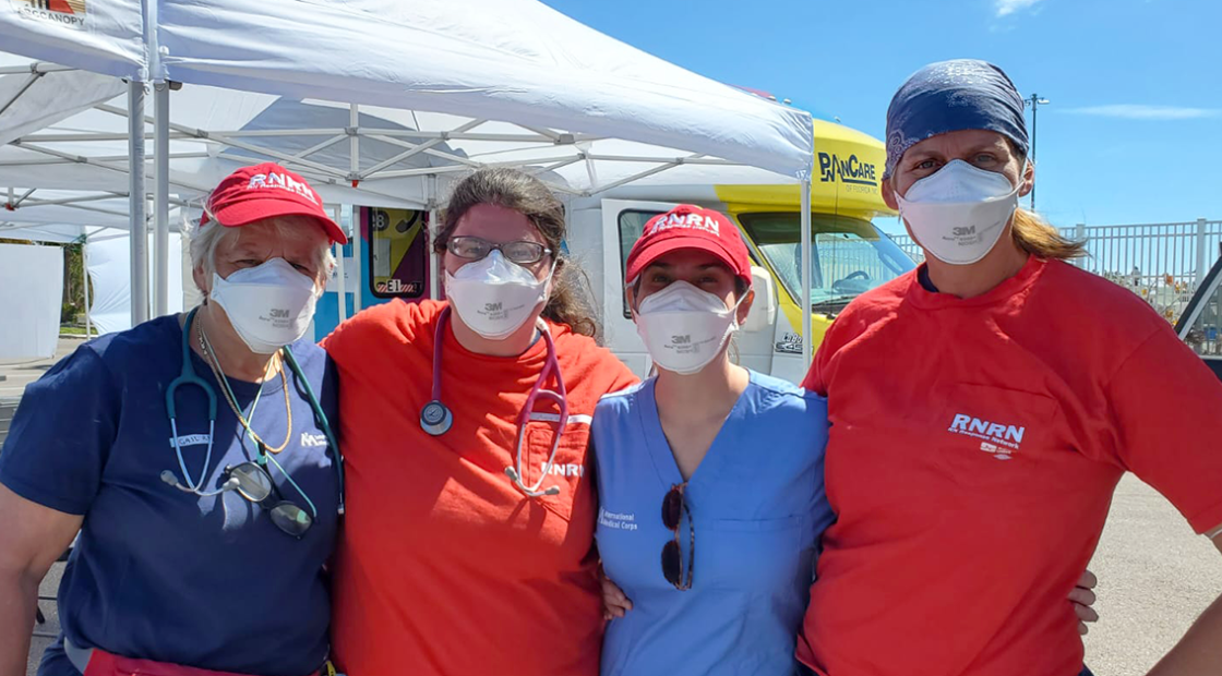 Four RNRN volunteers standing in front of tent