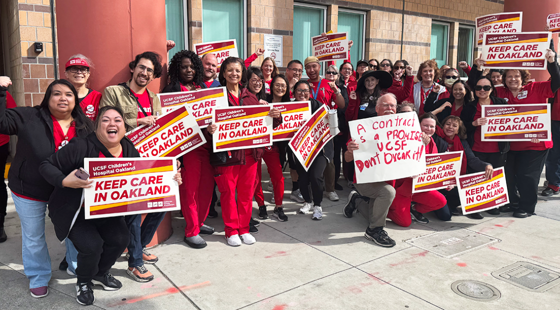 Large group of nurses holding signs "Keep care in Oakland"
