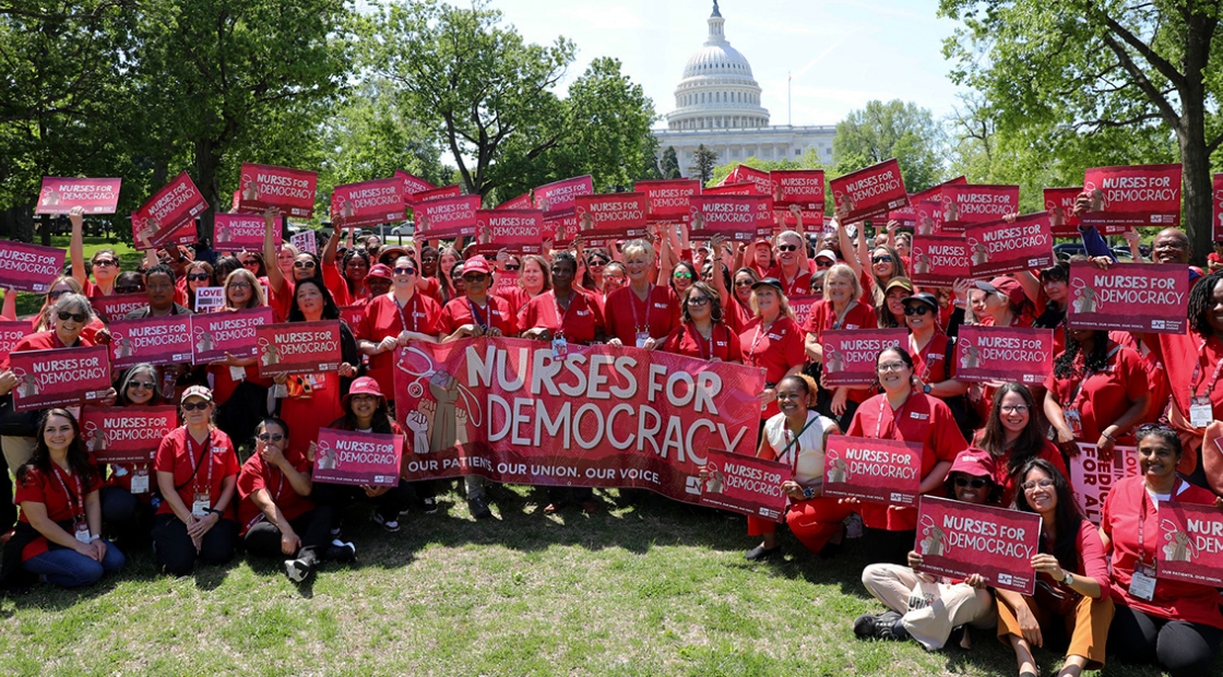 Group of nurses holding signs and banner "Nurses for Democracy"