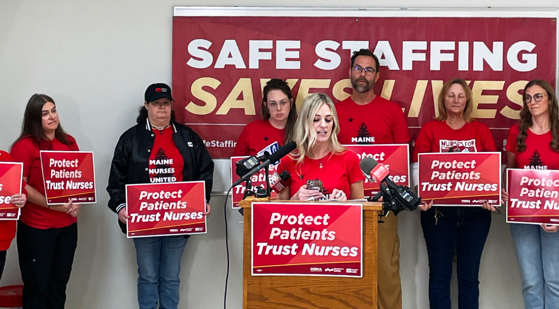 Nurses speaking at press event and holding signs "Protect Patients Trust Nurses" with banner in back "Safe staffing saves lives"