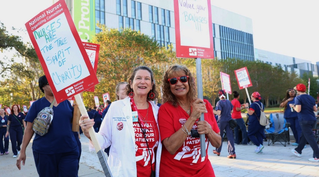 Nurses outside hospital holding signs "Nurses are the true spirit of charity"