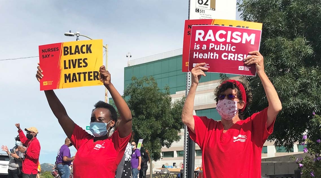 Nurses hold signs "Black Lives Matter" and "Racism is a public health crisis"