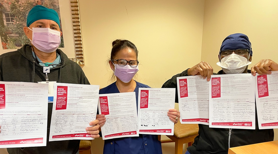 Three nurses inside hospital hold papers with signatures