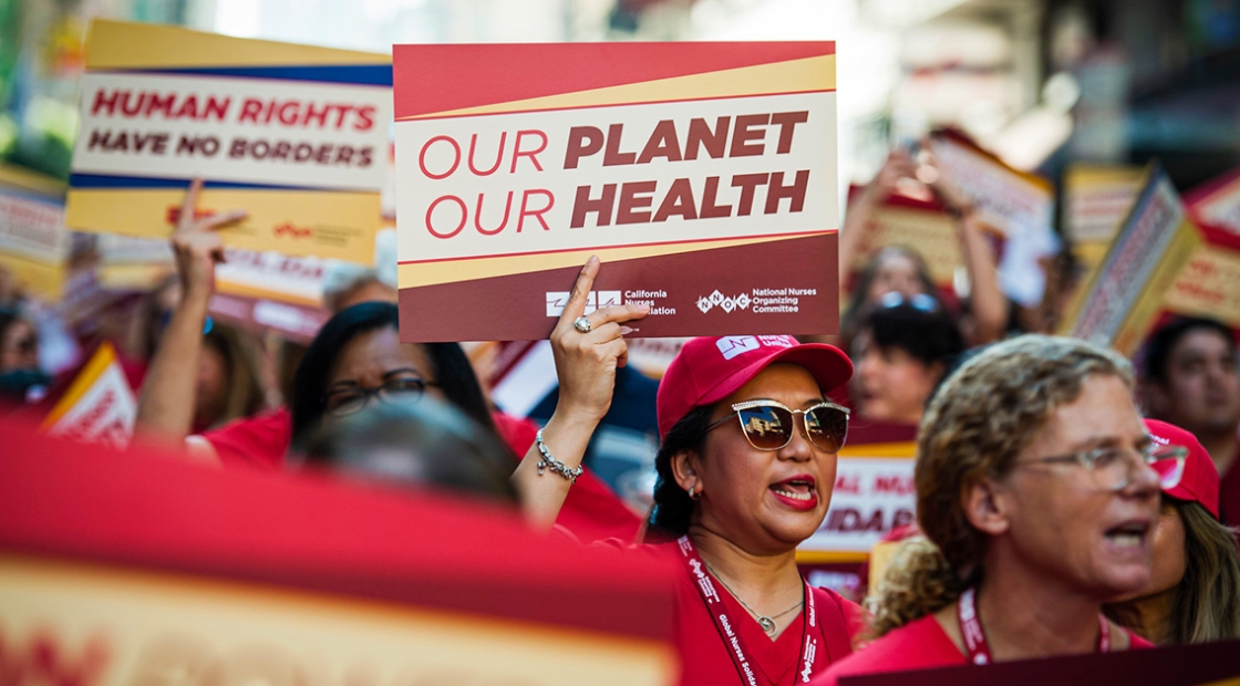 Nurse marching, one holds sign "Our Planet, Our Health"