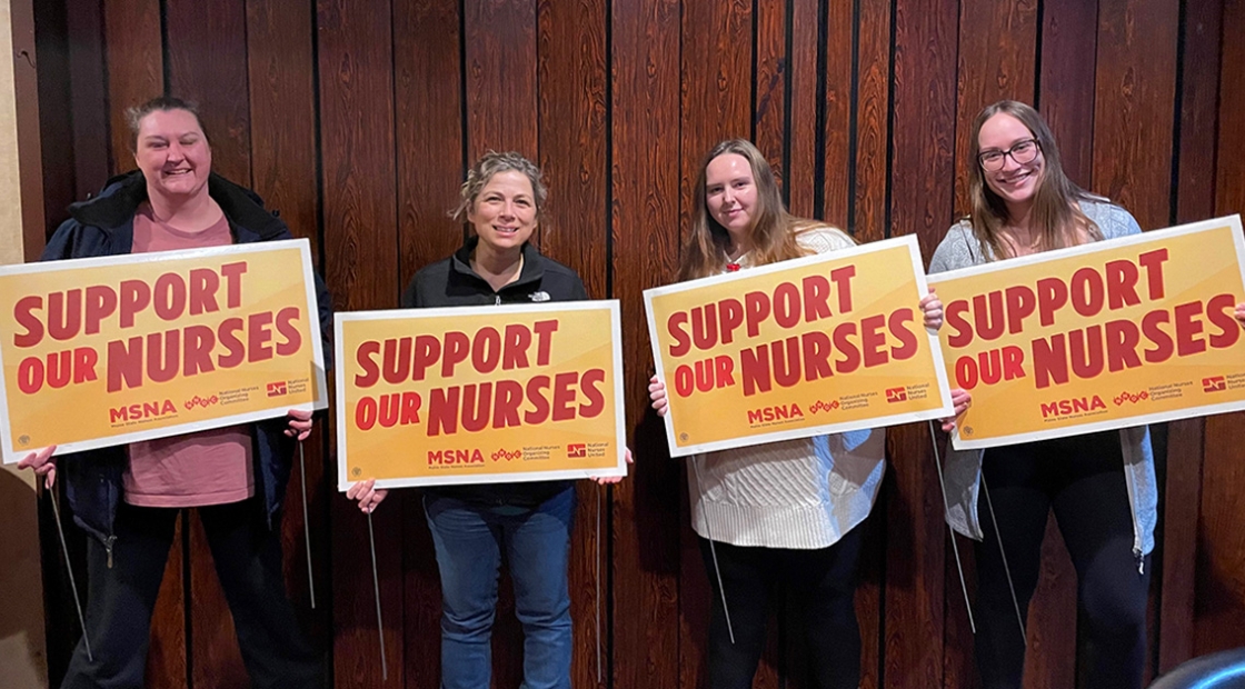Four nurses inside holding signs "Support Our Nurses"