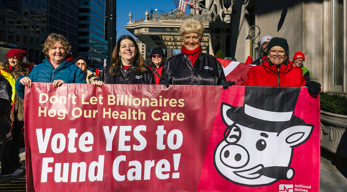 Four nurses outside holding banner "Vote YES to Fund Care"