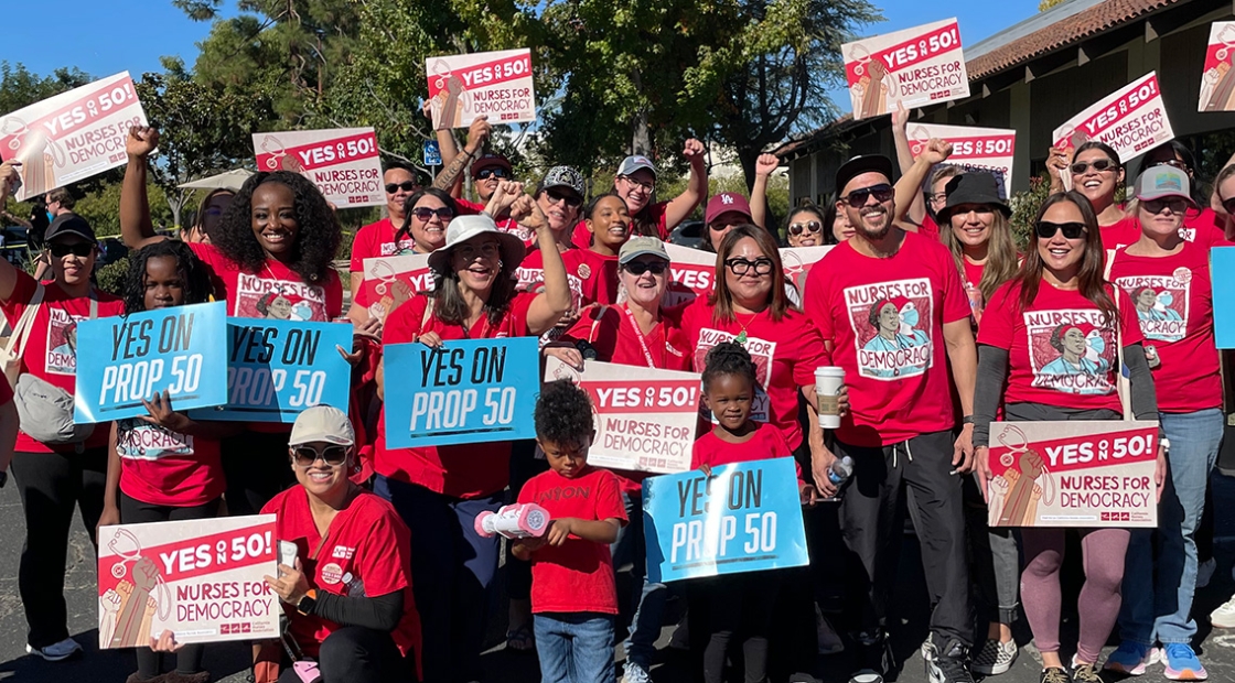 Large group of nurses and other canvassers holding signs "YES on Prop 50"