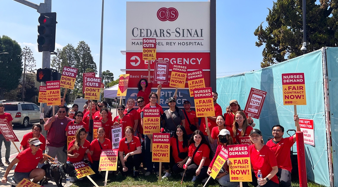 Nurses holding signs in front of Cedars-Sinai "Some cuts don't heal" and "Nurses demand a fair contract now"
