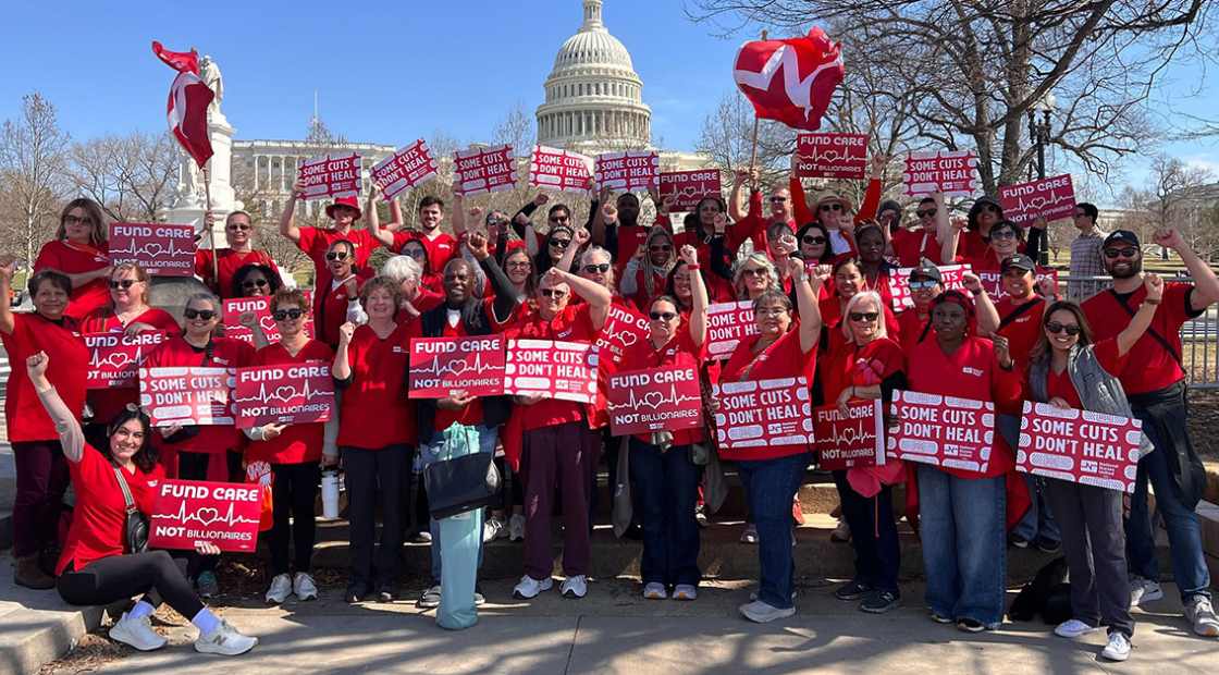 Large group of nurses outside capitol building holding signs "Some Cuts Don't Heal" and "Fund Care Not Billionaires"