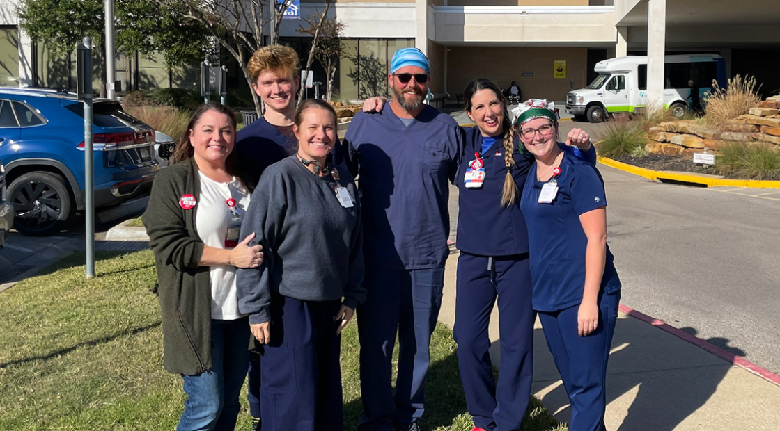 Six nurses outside hospital, smiling