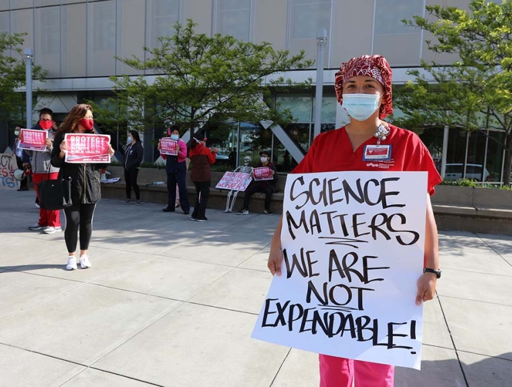 Nurse holds sign "Science Matters, We Are Not Disposable"