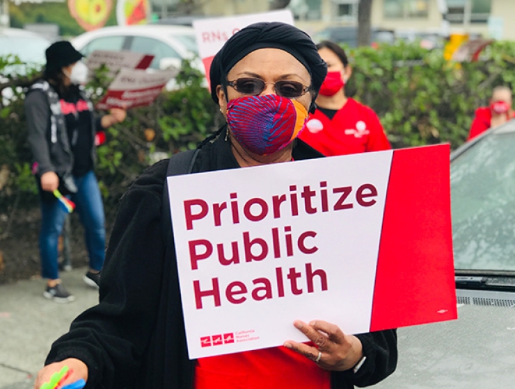 Nurse holds signs "Prioritize Public Health"