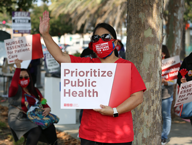 Nurse outside holds sign "Prioritize Public Health"