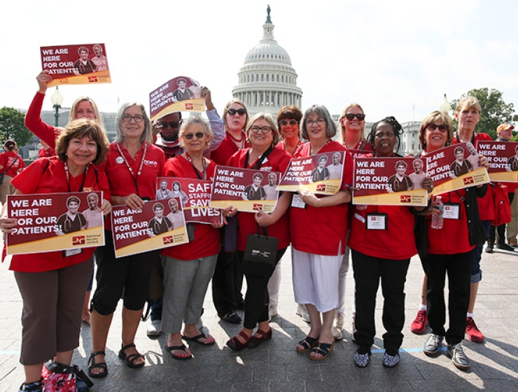 Large group of nurses outside Capitol Building hold signs "We are here for our patients"