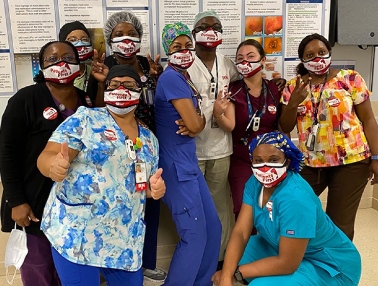 Large group of nurses inside hospital giving thumbs up