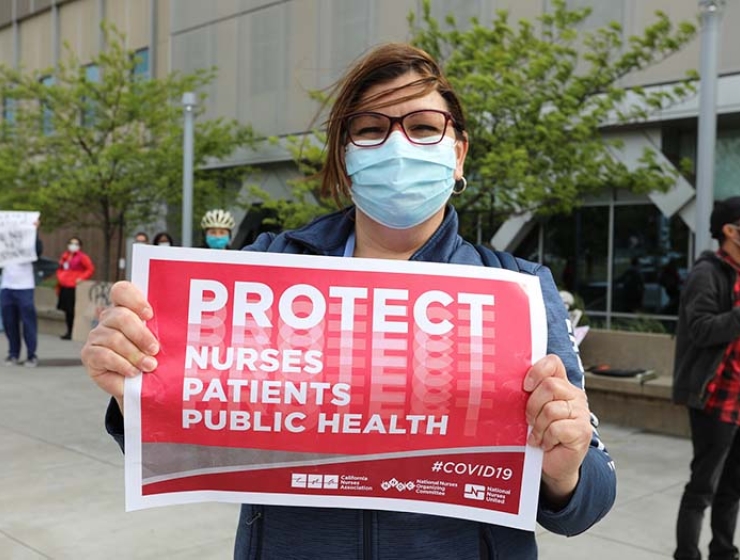 Nurse holds sign "Protect Nurses, Patients, Public Health"