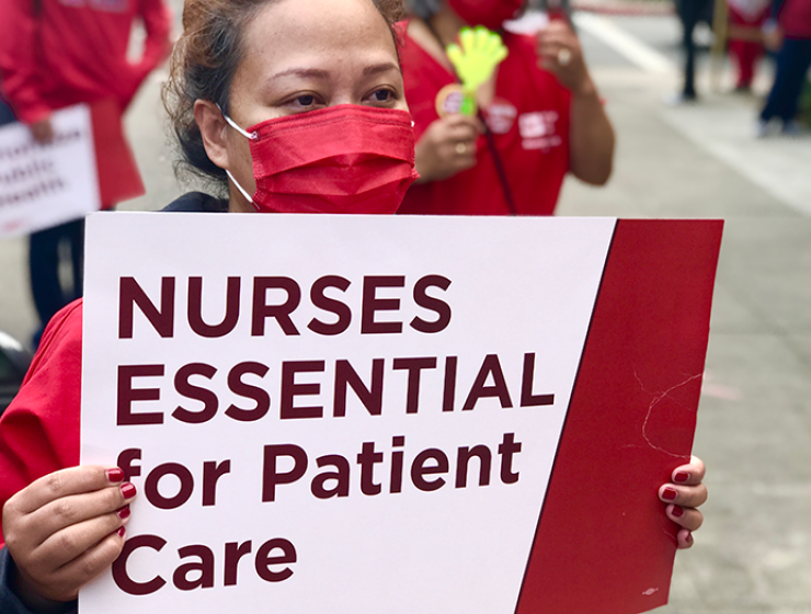Nurse holds sign "Nurses essential for patient care"