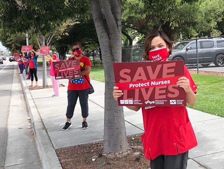 Nurses hold signs "Save Lives: Protect Nurses"