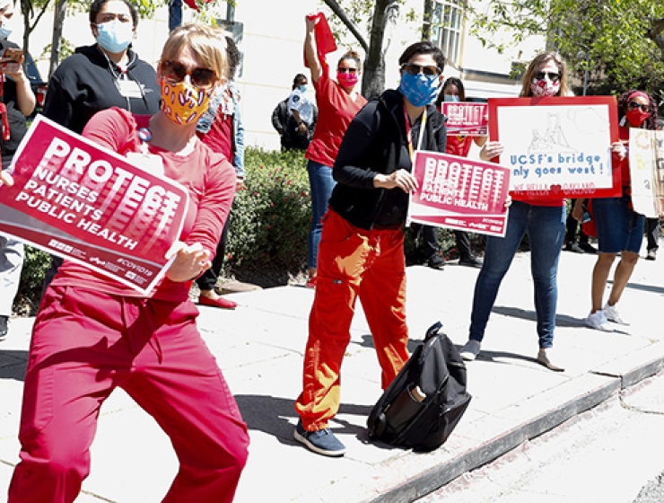 Nurses holding signs along street "Protect Nurses, Patients, Public Health"