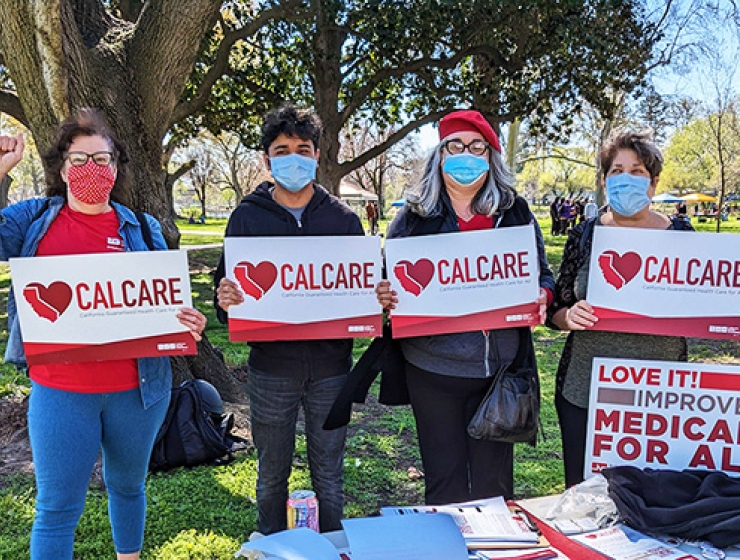 Group of four people all holding CalCare signs