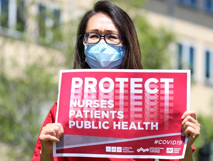 Nurse holds sign "Protect Nurses, Patients, Public Health"