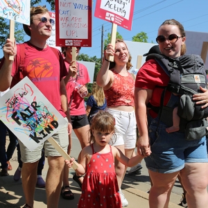 Family on picket line holding signs encouraging Ascension to be fair and kind