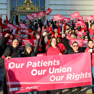 Large group of nurses holding signs and banner "Our Patients, Our Union, Our Rights"