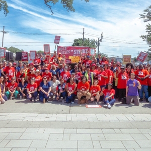 Large group of nurses outside behind banner "NOLA Nurses On Strike"