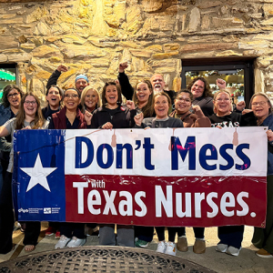 Large group of nurses in street clothes, holding banner "Don't Mess With Texas Nurses"