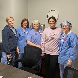 Four nurses inside hospital, standing side-by-side, smiling